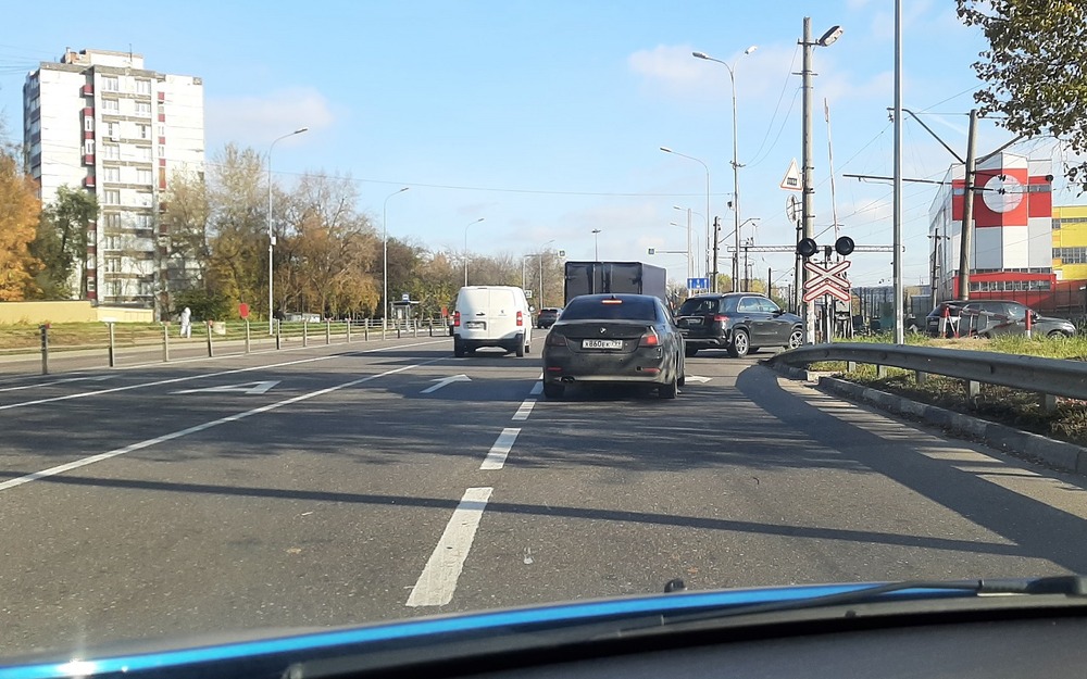 Автомобиль находится у самого начала прерывистой линии, которая заканчивается возле переднего колеса едущего впереди BMW.